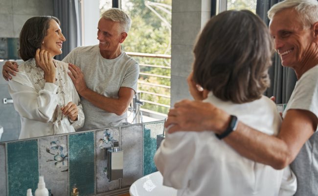 Couple smiling at each other in front of a mirror.