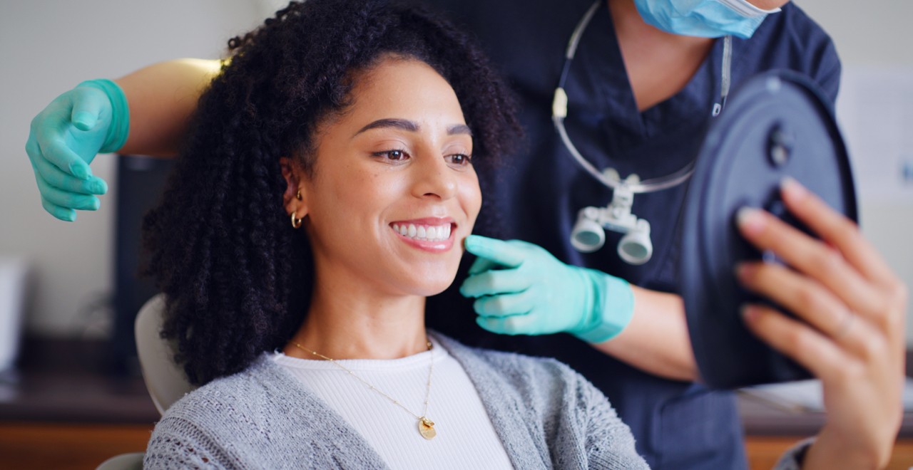 Woman smiling in dentist chair holding up mirror